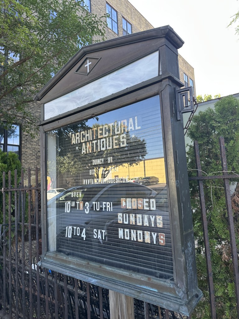 Architectural Antiques salvage shop sign on Quincy Street, showing business hours and contact information