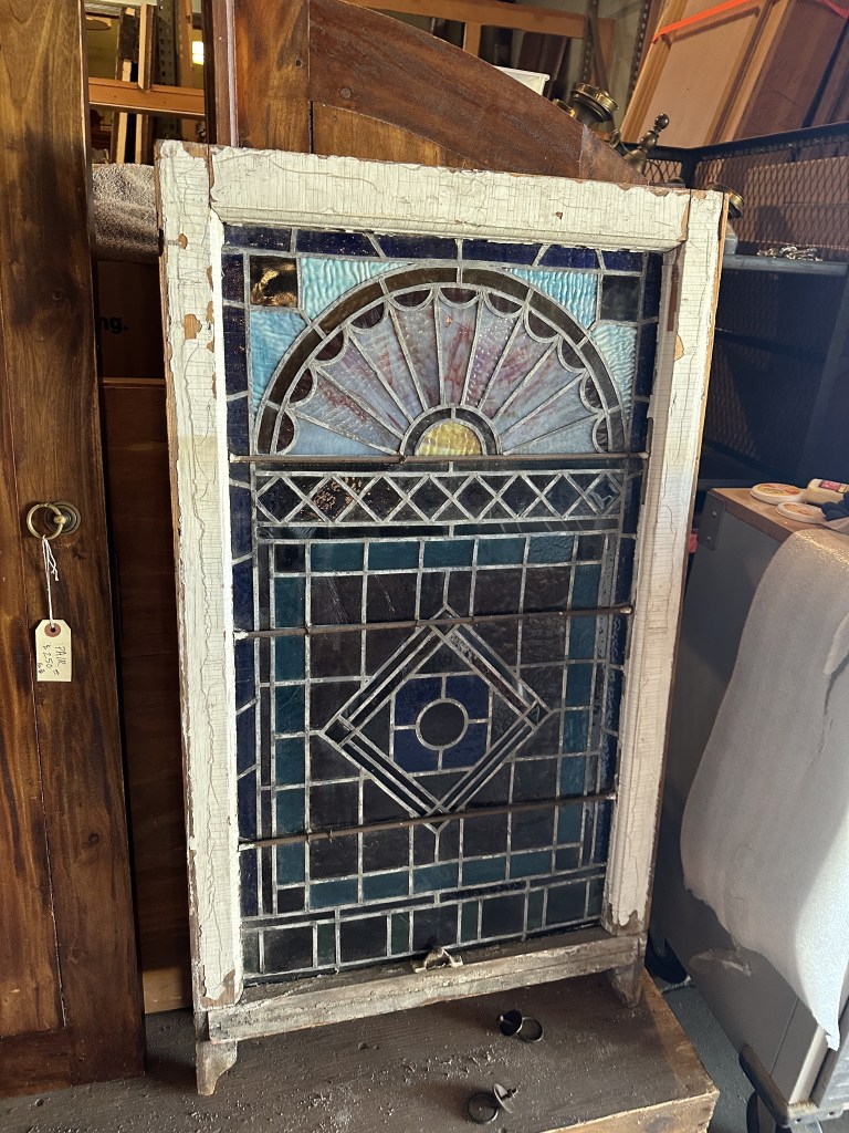 Antique leaded stained-glass window with an arched fan pattern at an architectural salvage shop